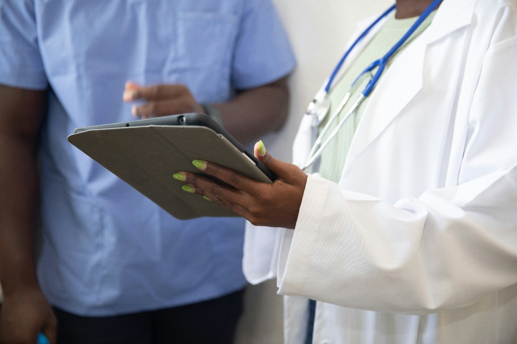 Medical professional reviewing care information on a tablet with a colleague